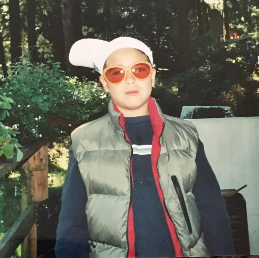 As a kid in red sunglasses and a puffer vest